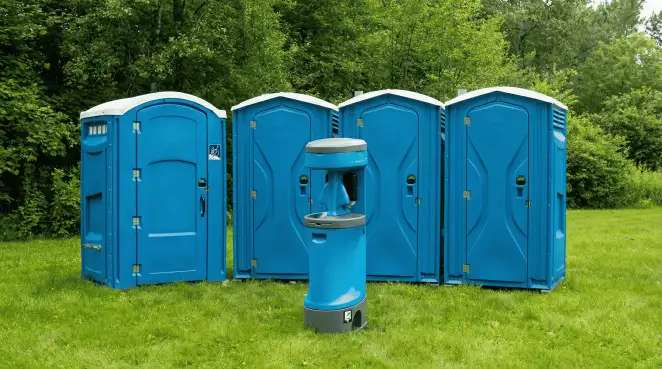 Four blue portable toilets and a matching hand washing station on grass near trees, a common sight at local outdoor events in Allentown, PA